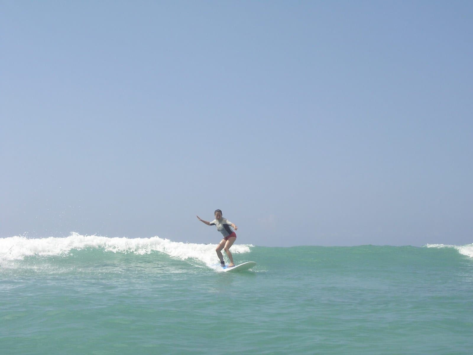 Dr. Sonya Kim surfing a turquoise wave